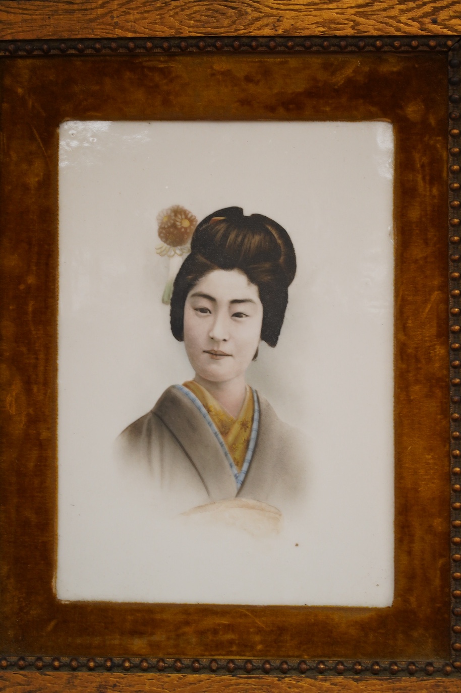 A framed Japanese painted porcelain plaque of a Geisha, 24cm wide, 33cm high. Condition - fair